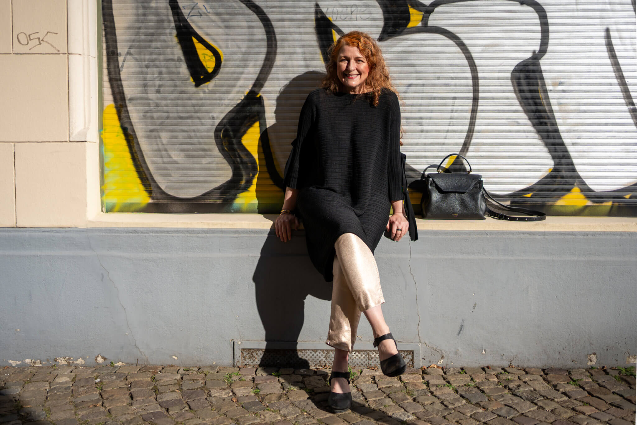 Streetstyle-Foto einer stylerebelles Modebloggerin über 50 mit Annette-Görtz-Kleid, goldener Jeans und kleiner ALEMI Zurich Viadukt Ledertasche.