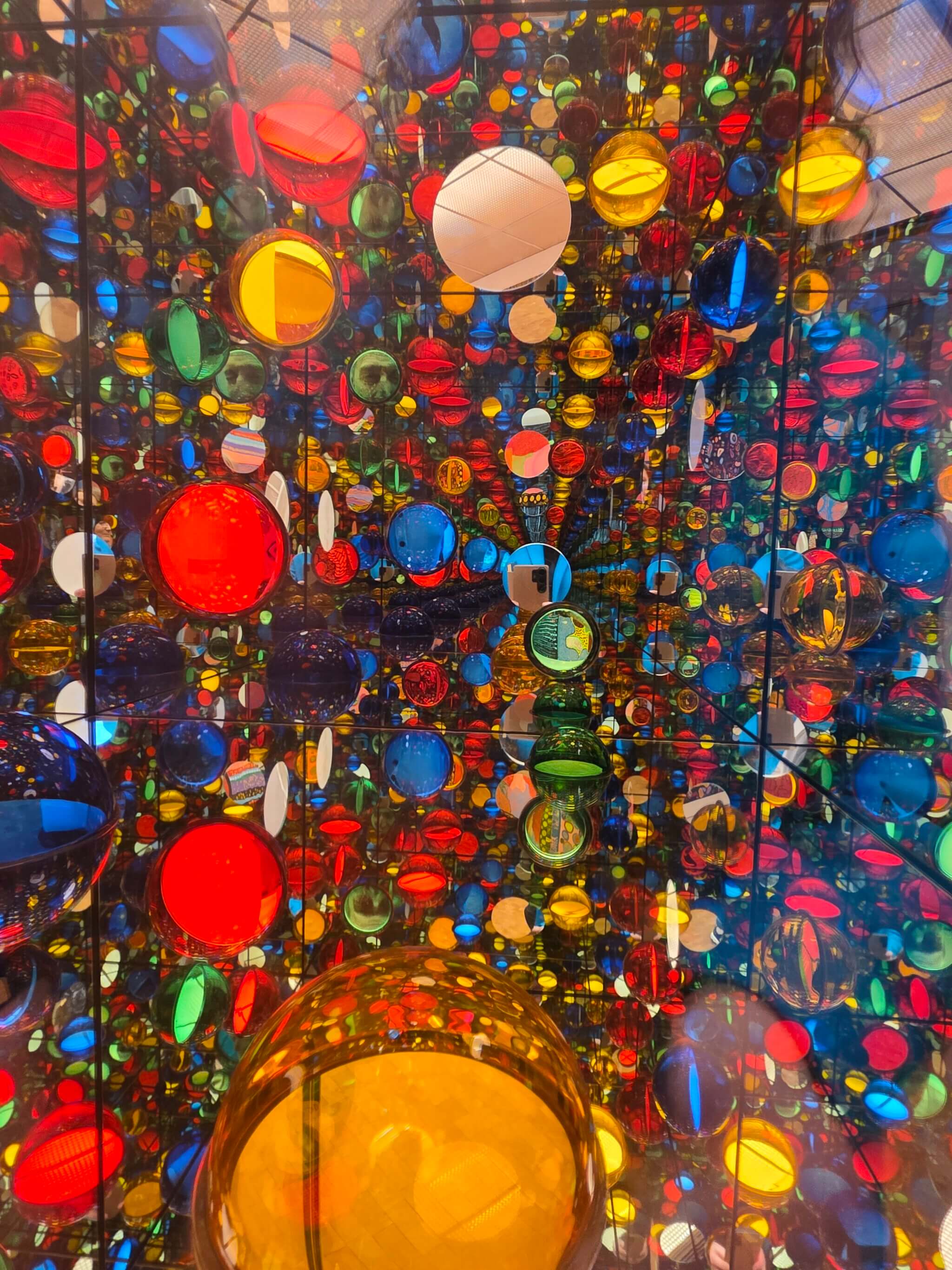 Der Infinity Room mit seinen organischen, gepunkteten Formen zählt zu den Highlights der Kusama-Ausstellung im Museum Ludwig. Spiegelungen, Licht und die ikonischen Polka Dots schaffen ein immersives Kunsterlebnis, das Besucher:innen komplett eintauchen lässt.