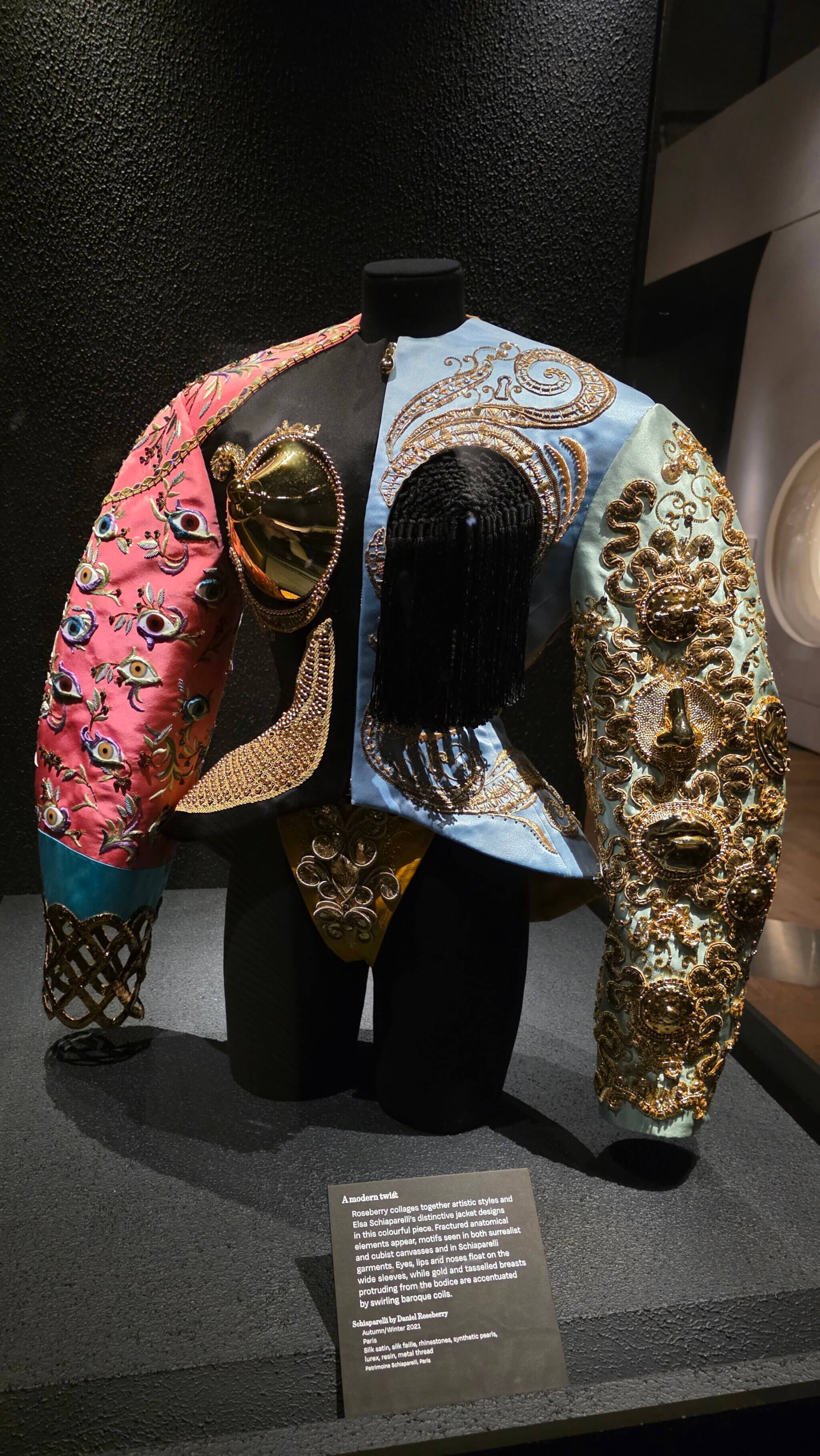 Bunte Jacke mit Augen, Lippen, Nase, goldenen Körpermotiven und Quasten -  sichtbare Brücke zwischen Elsa Schiaparelli und Daniel Roseberry im V&A London
