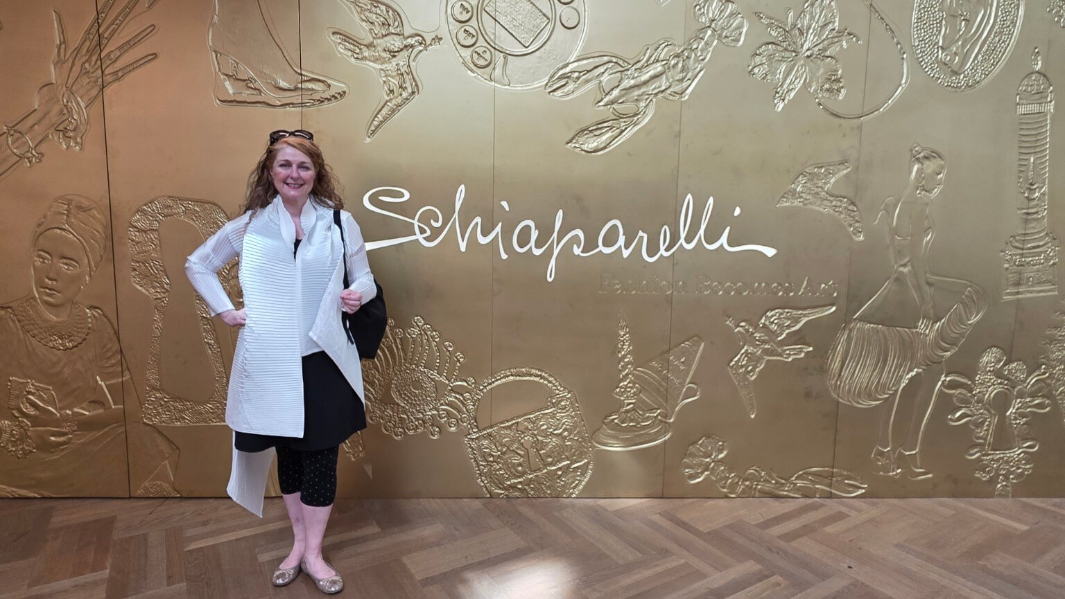 Besuch der Schiaparelli-Ausstellung im V&A in London vor der goldenen Schiaparelli-Wand